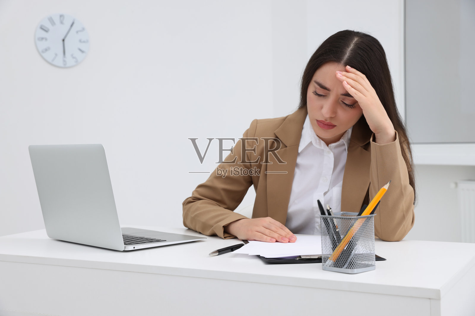 不开心的年轻女实习生坐在办公室的桌子旁照片摄影图片