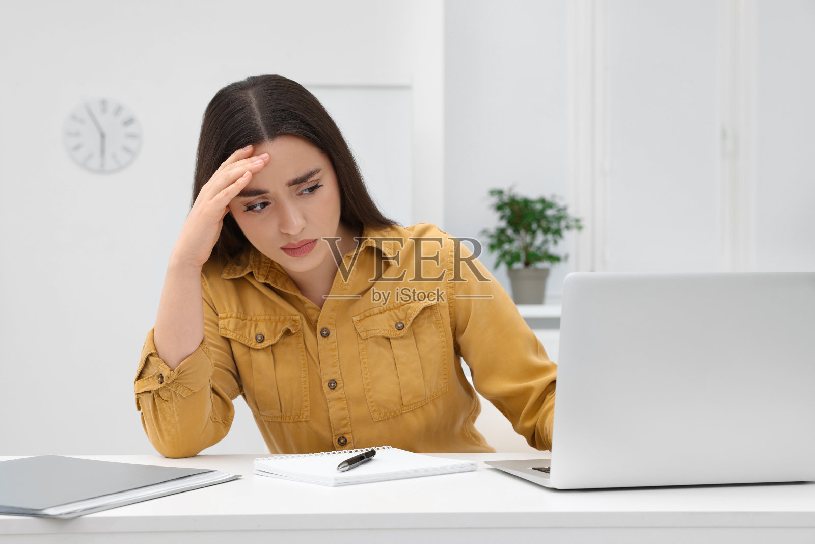 不开心的年轻女实习生坐在办公室的桌子旁照片摄影图片