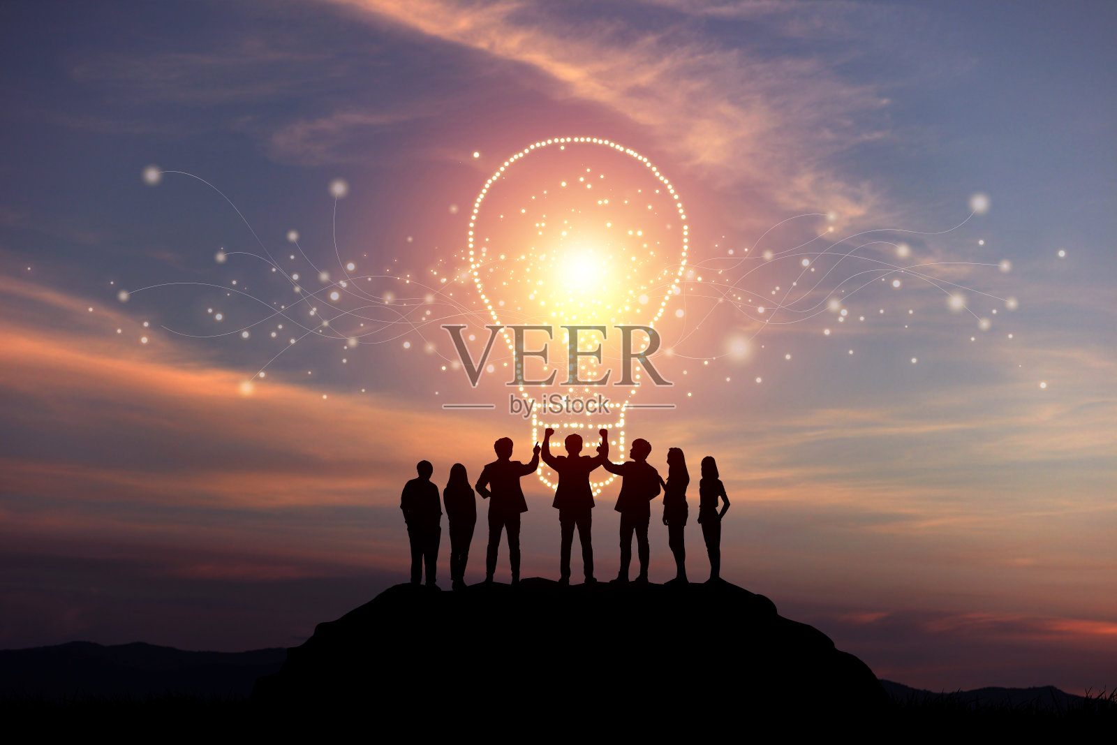 商人们集思广益的剪影，灯光汇聚成创意灯泡的形状。照片摄影图片