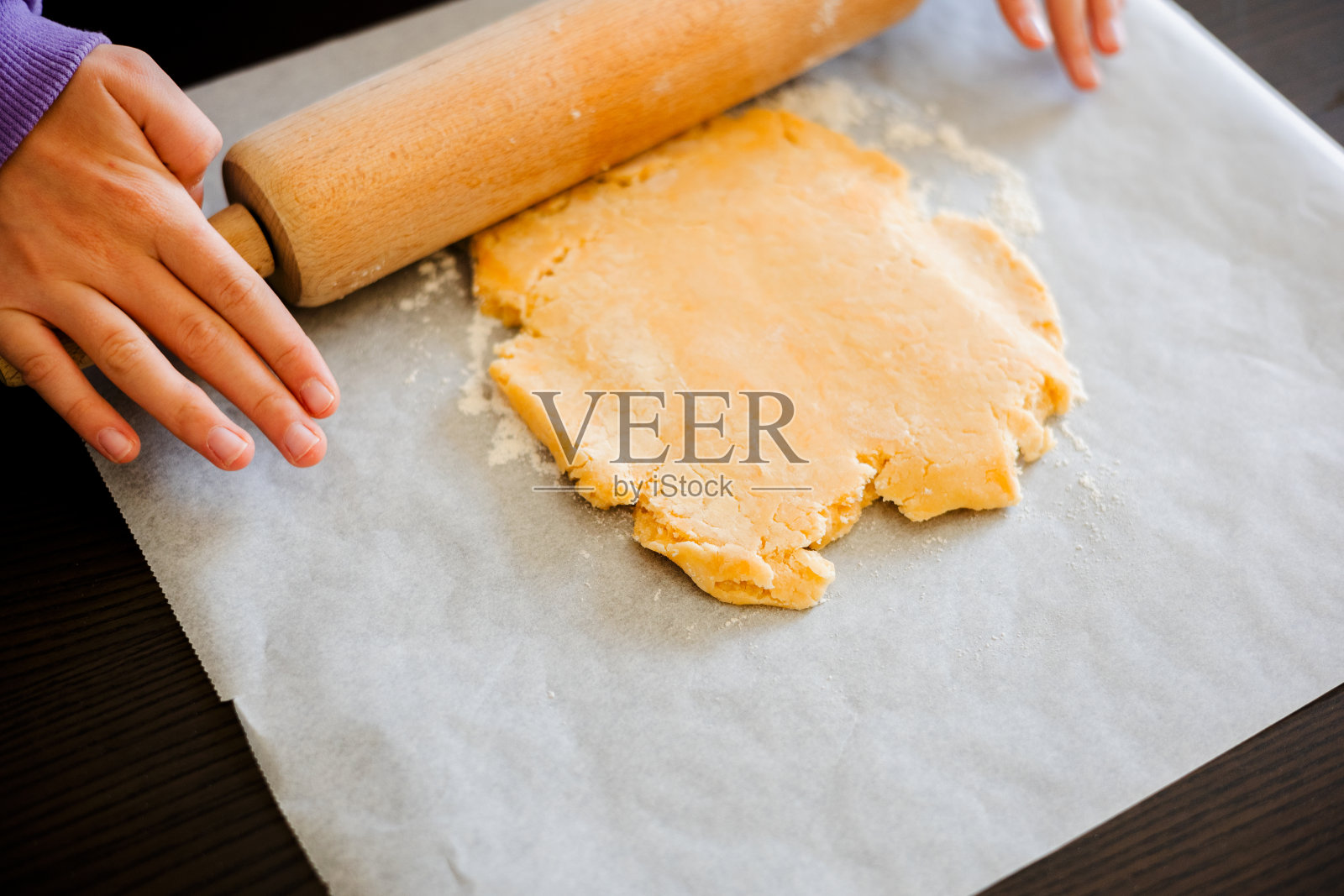 孩子的手在近距离擀酥皮面团照片摄影图片