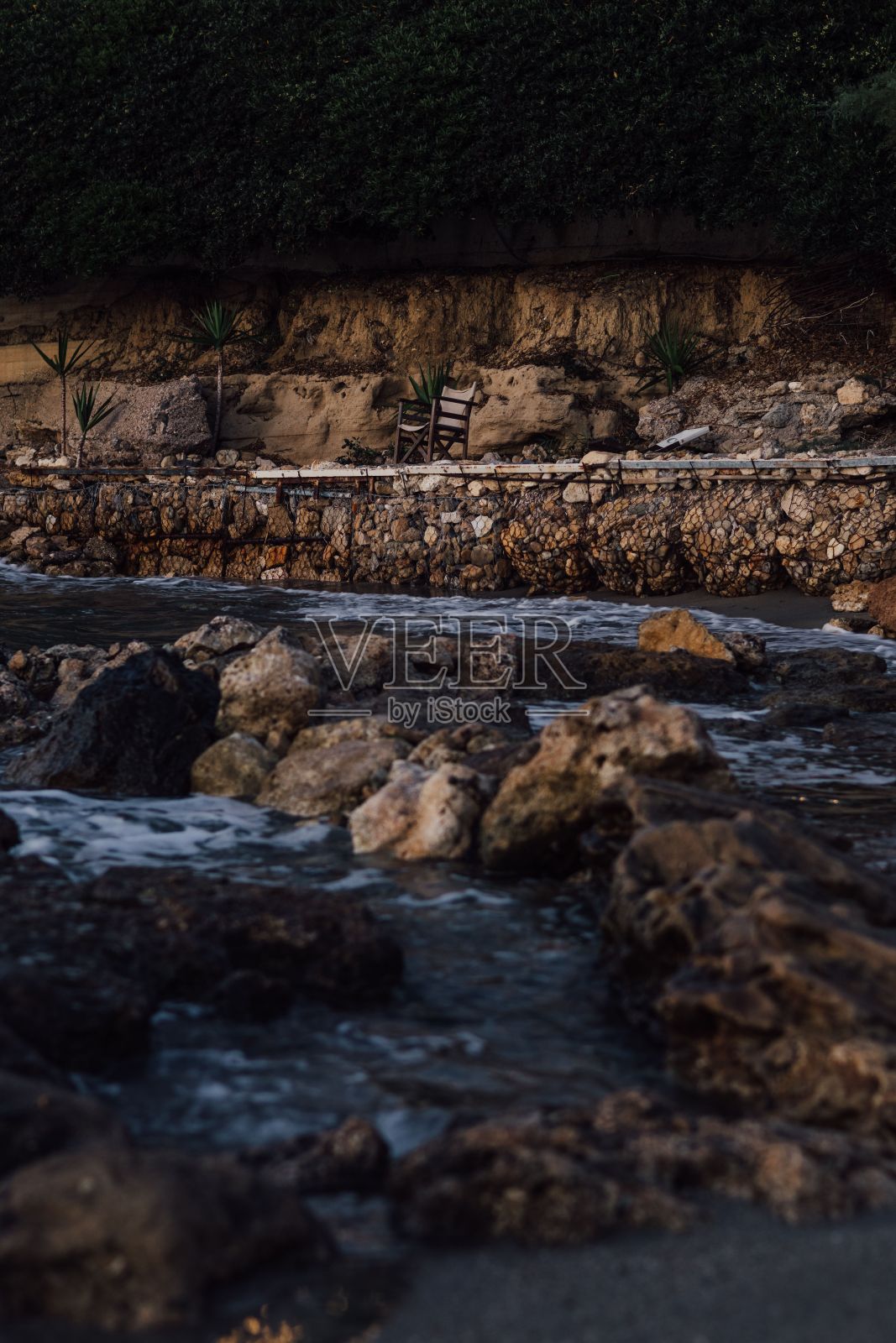 坐在希腊海岸的岩石沙滩上，俯瞰地中海照片摄影图片