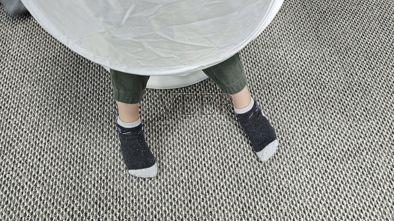 婴儿穿着袜子的脚挂在椅子上，背景是铺着地毯的地板。照片摄影图片