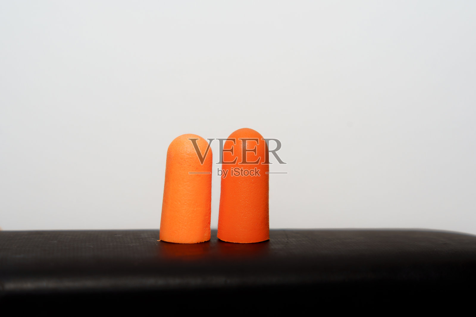 黑色底座上的橙色耳塞照片摄影图片