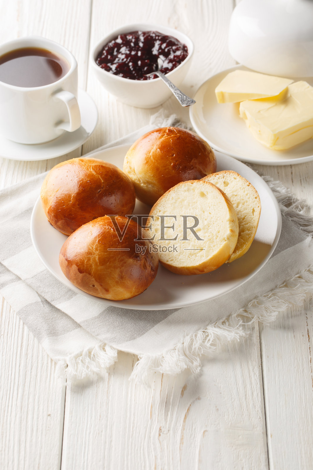 挪威小豆蔻卷配上黄油、果酱和咖啡(餐桌特写)。垂直照片摄影图片