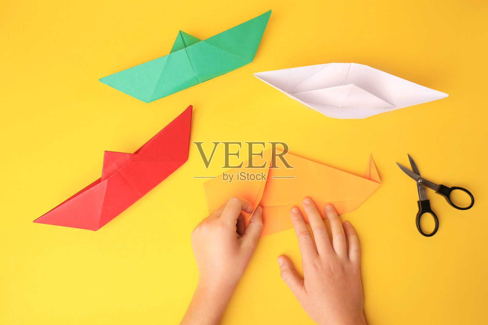 折纸艺术。儿童折叠纸黄色背景，特写和顶视图照片摄影图片