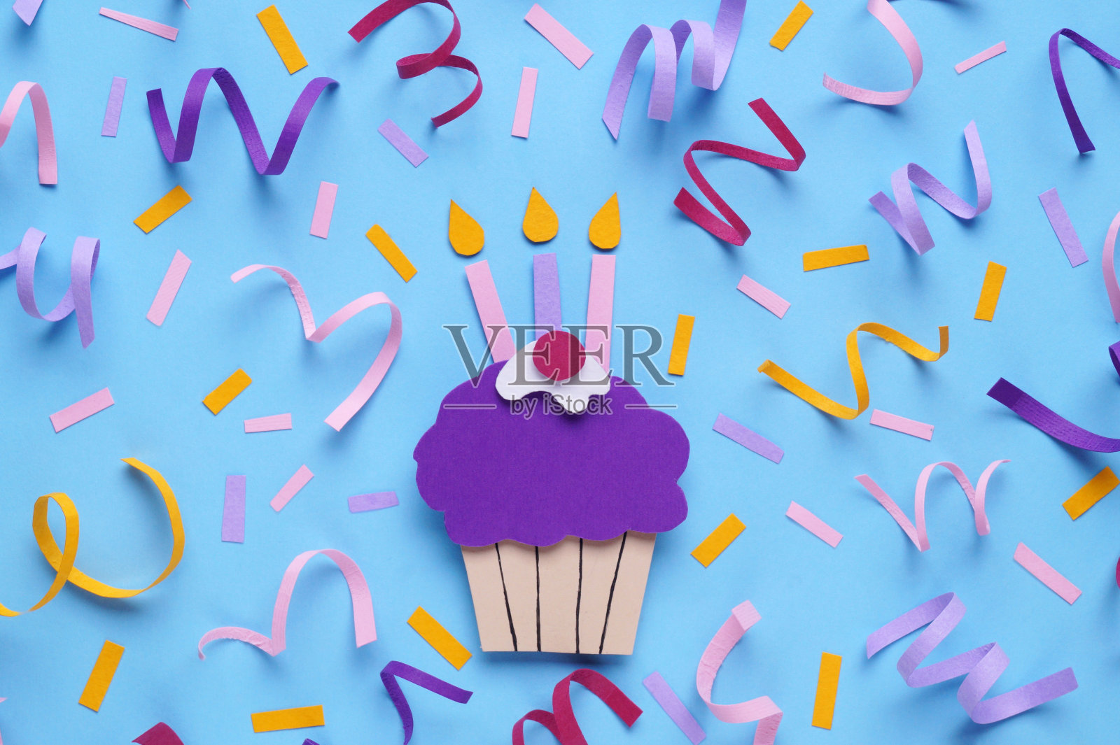 生日聚会。浅蓝色背景的纸杯蛋糕，放上蜡烛和五彩纸屑，平放照片摄影图片