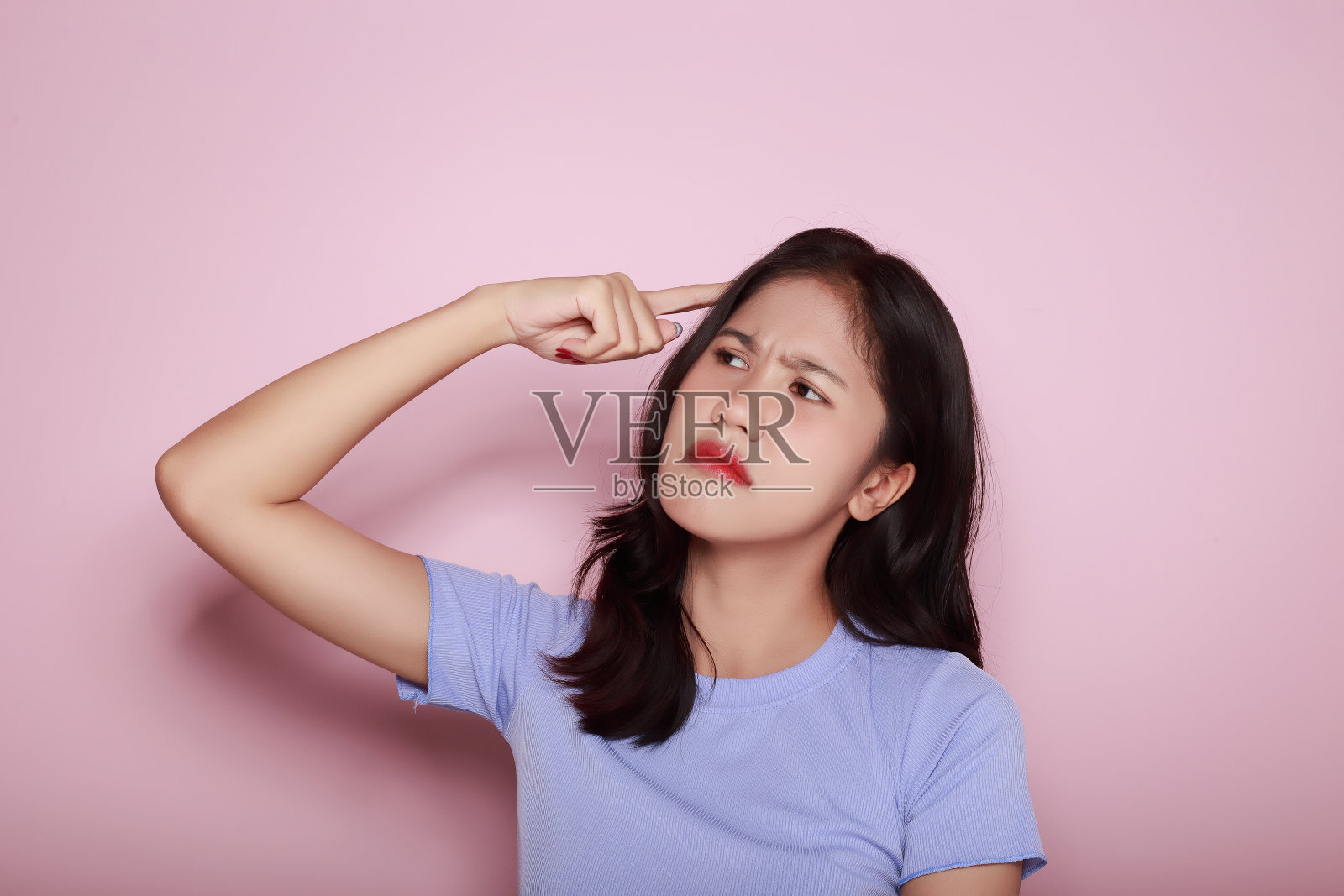 一个美丽的年轻女子的肖像在浅粉色的背景，快乐和微笑，张贴在站立的位置，半身照片的好积极的女士，肖像的一个友好的年轻女子笑得很开心。照片摄影图片