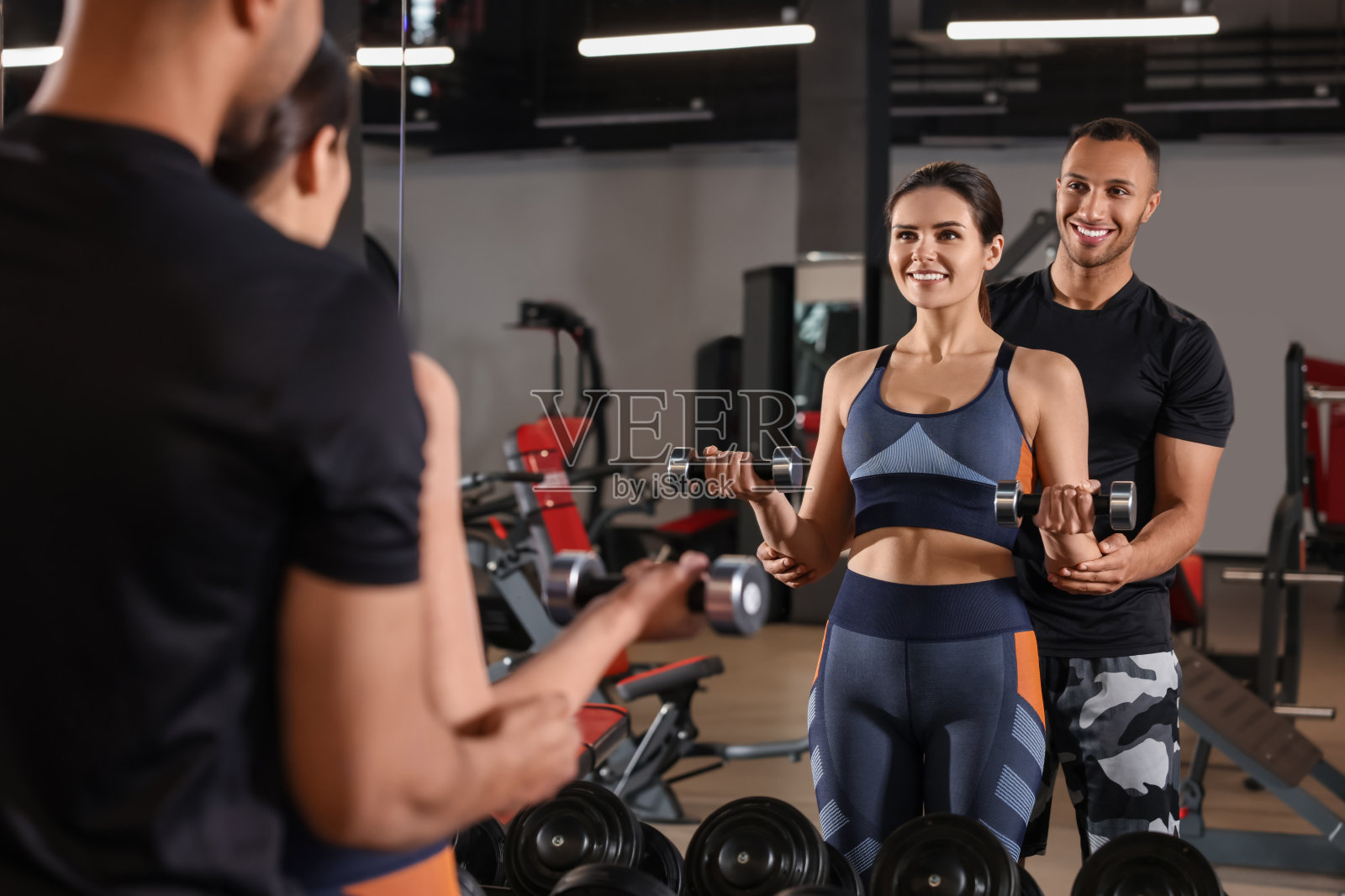 快乐的教练向女性展示如何在现代健身房正确锻炼照片摄影图片