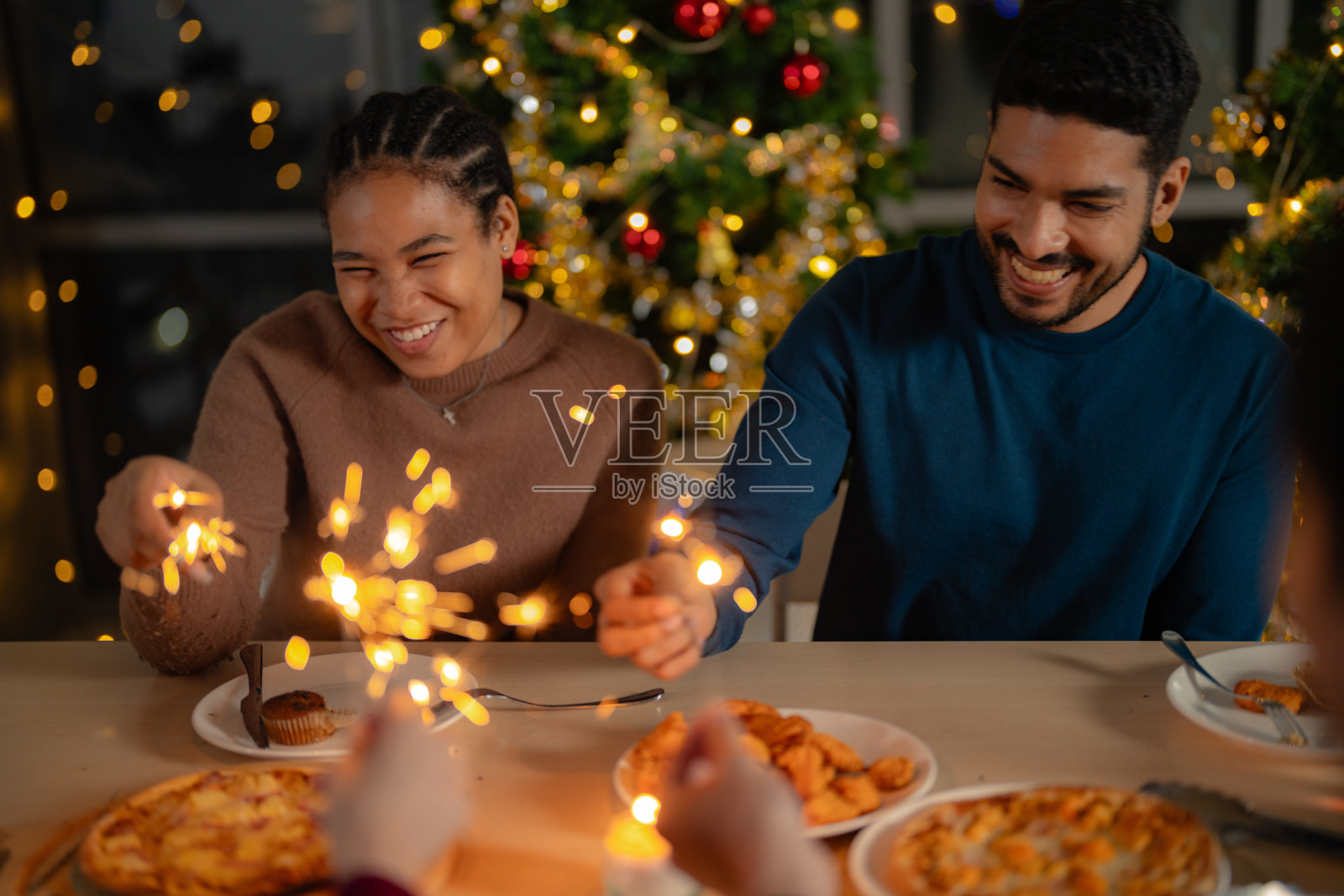男男女女在一个有圣诞树的聚会上拿着烟花。年轻夫妇亚洲人喜欢庆祝圣诞节和新年。欢天喜地，用美食、美酒和友谊为爱庆祝;照片摄影图片