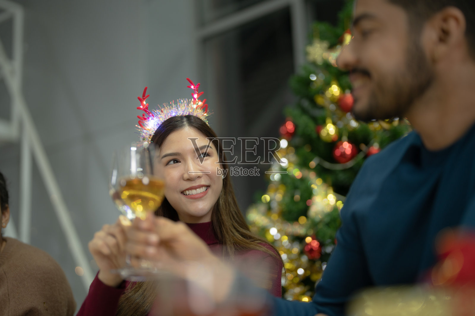 近距离的女孩拿着香槟杯与照明。喝香槟的晚宴。手里拿着清澈的玻璃杯，酒精在黄色的映照下闪闪发光。照片摄影图片