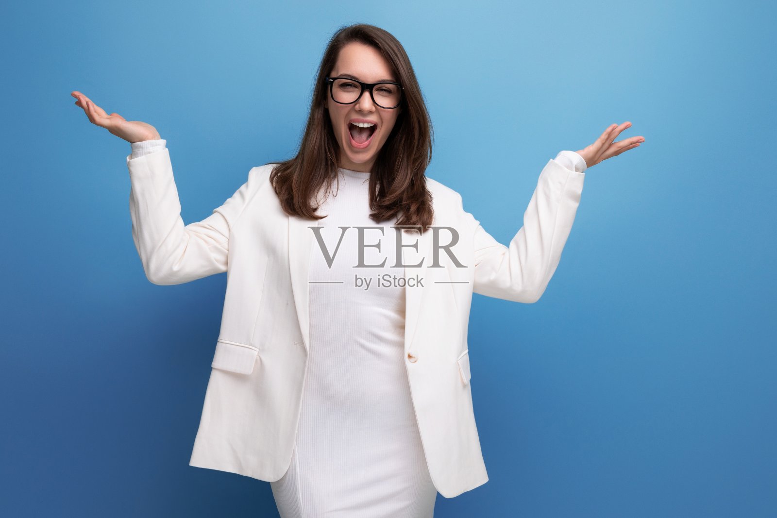 精力充沛的黑发女子在工作室背景的白色连衣裙照片摄影图片