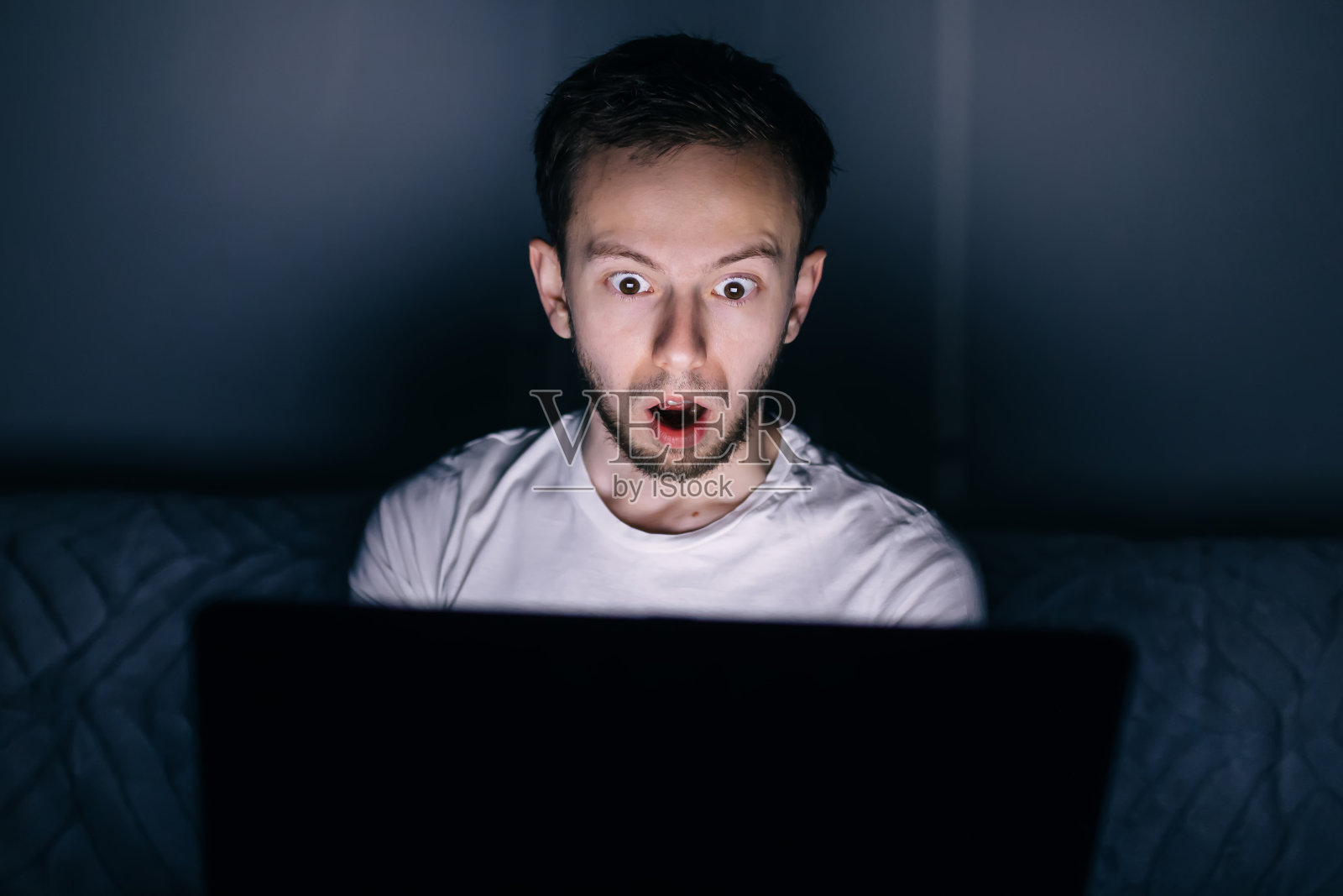 晚上盯着笔记本电脑屏幕的人惊呆了照片摄影图片
