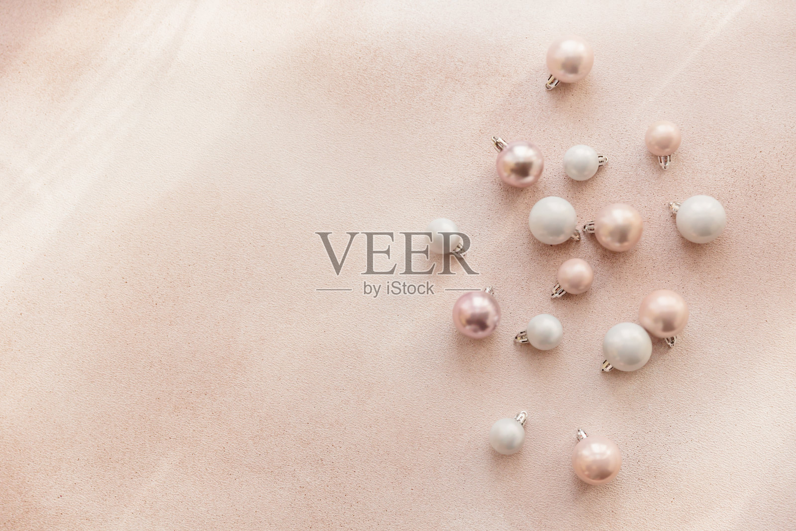 白色和粉色的圣诞球散落在米色的背景上照片摄影图片