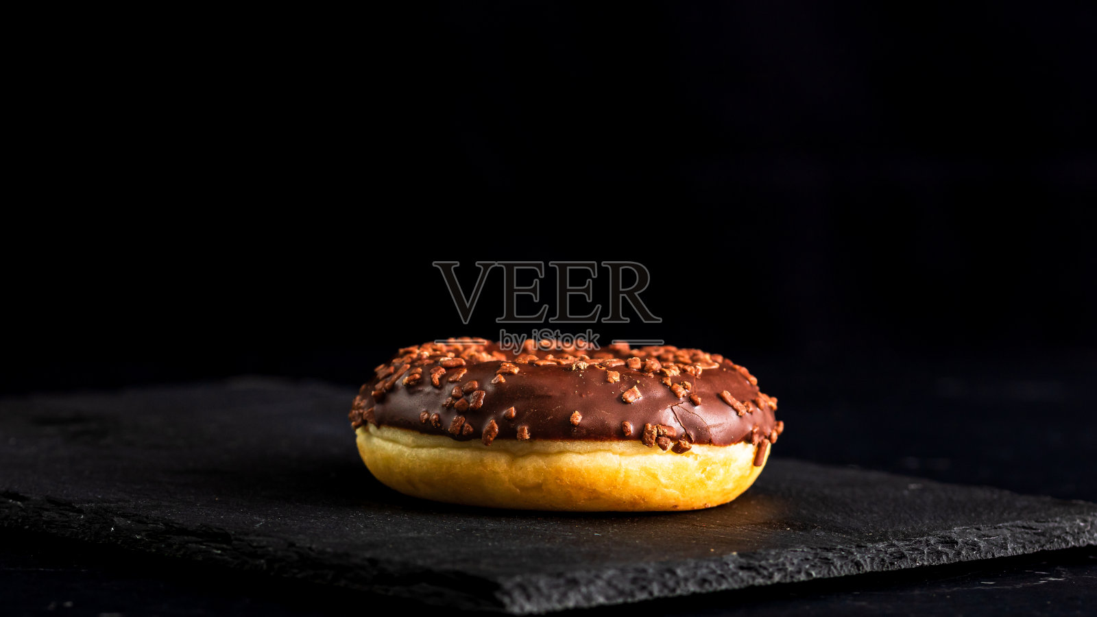 巧克力釉面甜甜圈与巧克力碎片分离。美味甜甜圈的特写。照片摄影图片