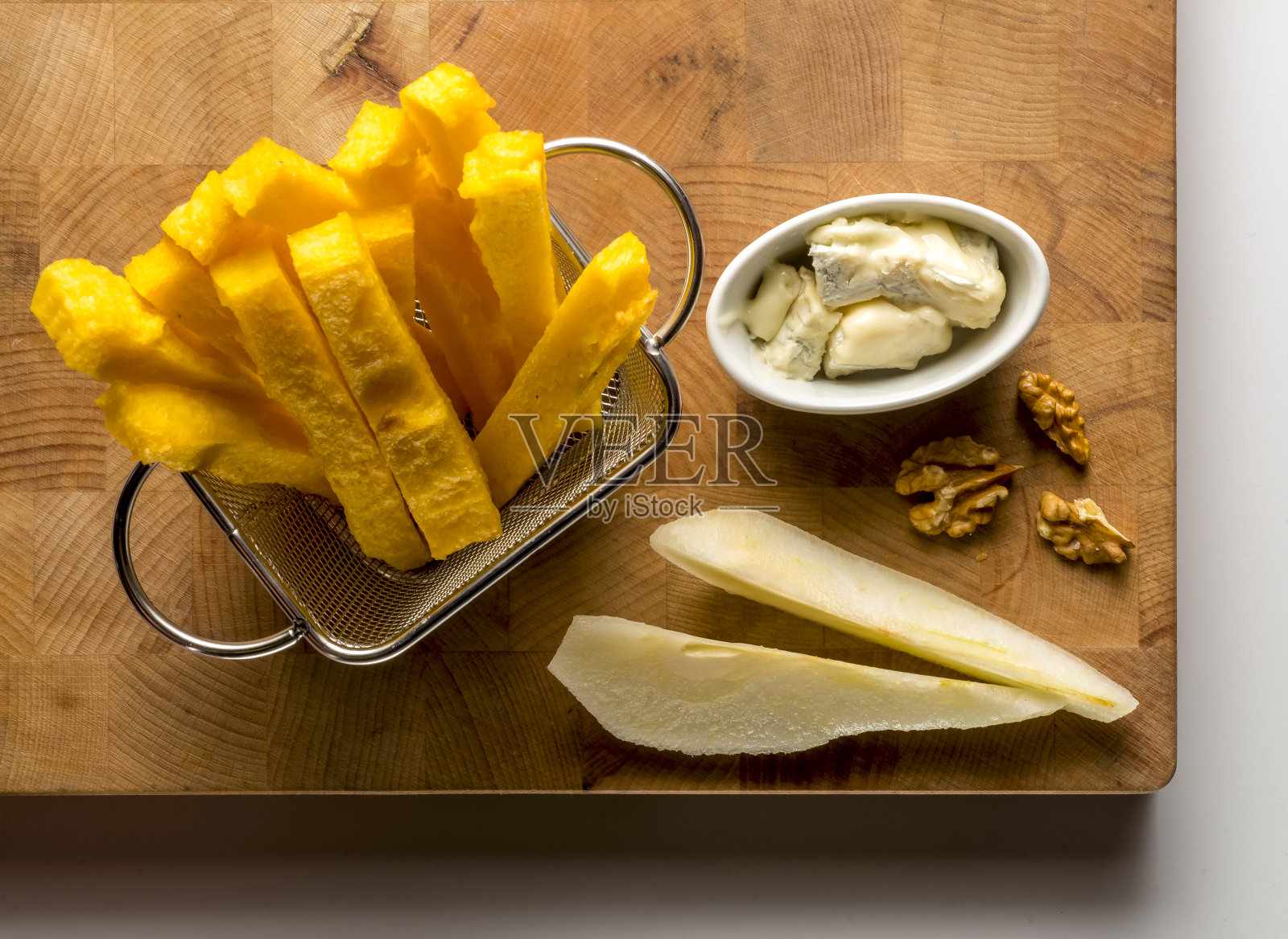 木制砧板，上面有玉米粥、梨、坚果和奶酪照片摄影图片