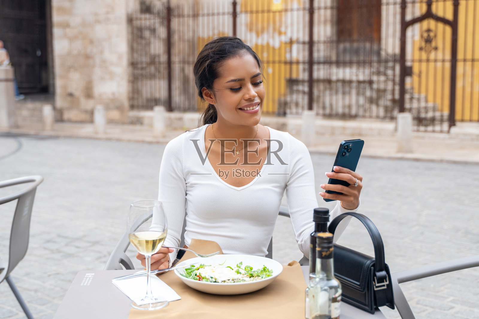 年轻的拉丁裔妇女坐在美丽的露台咖啡馆里吃健康的食物。年轻女孩吃素，喜欢吃蔬菜沙拉。健康饮食的理念，节食照片摄影图片