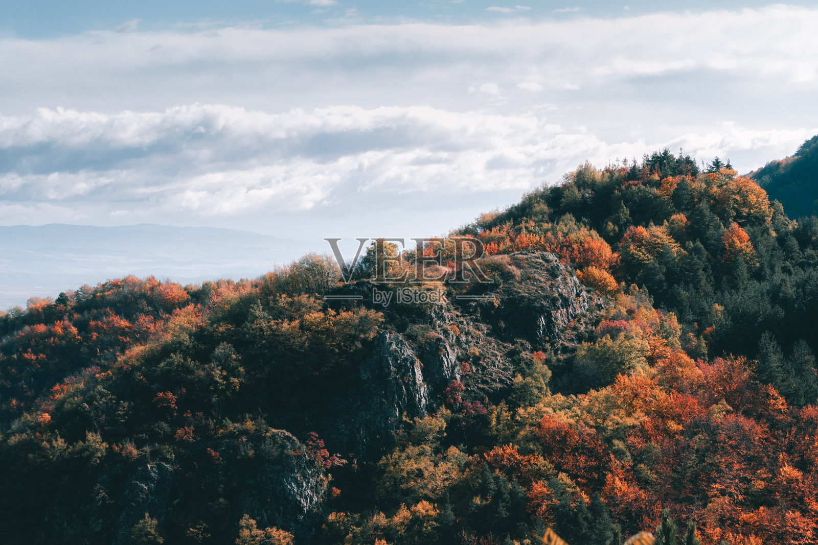 美丽的岩石景观和许多充满活力的树木与多云的背景。照片摄影图片