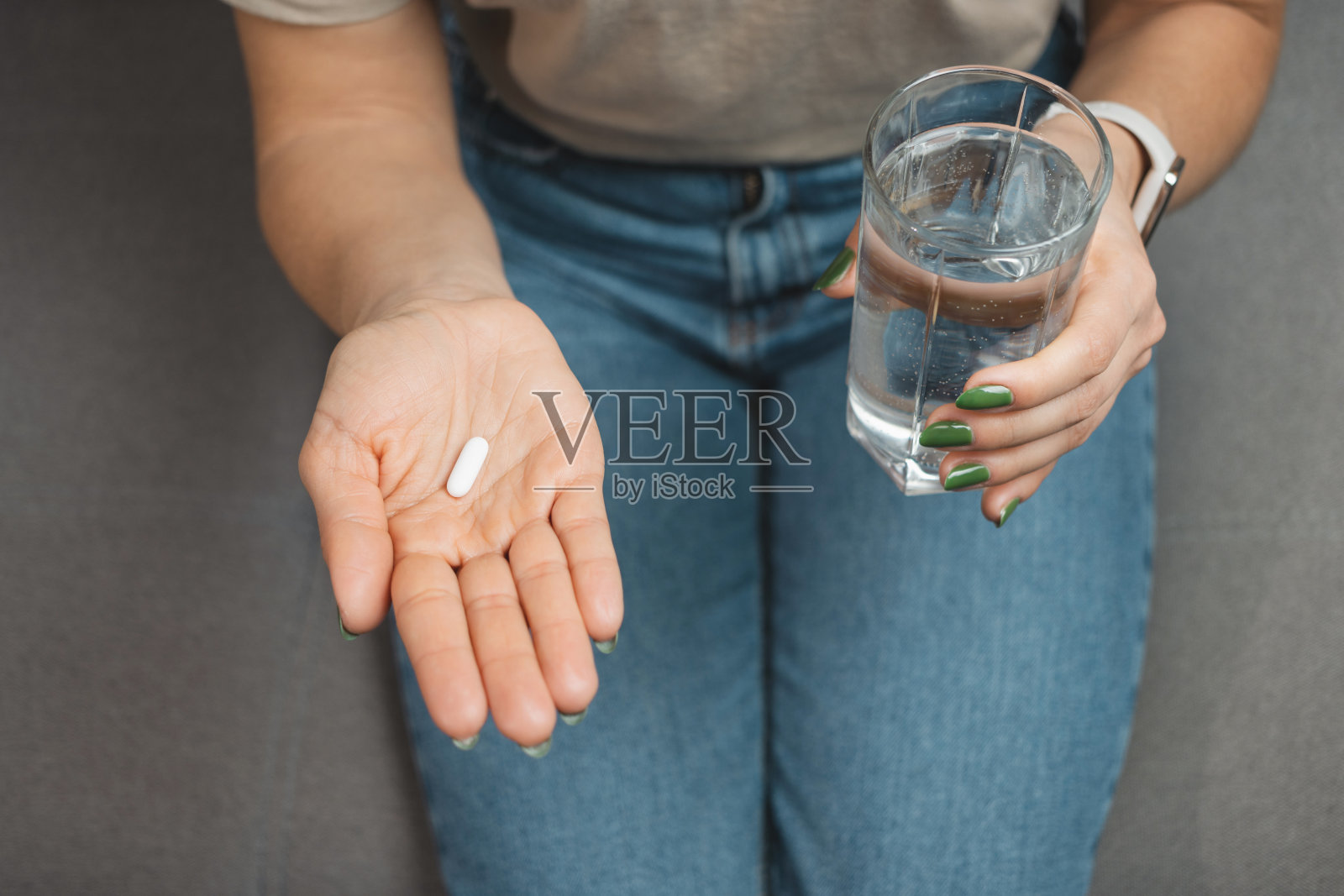 年轻女子正在服药，白色药丸，手里拿着一杯水，特写照片摄影图片