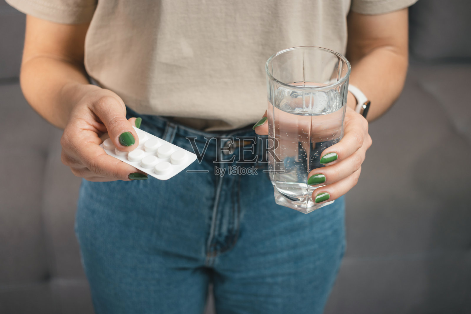 年轻女子拿着药，泡罩装着治疗用的药片和一杯水，特写照片摄影图片
