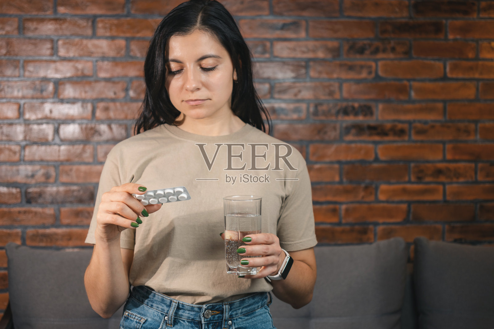 年轻貌美的女子手里拿着药，泡罩包里装着治疗用的药片和一杯水，放在家里，重点放在手上照片摄影图片