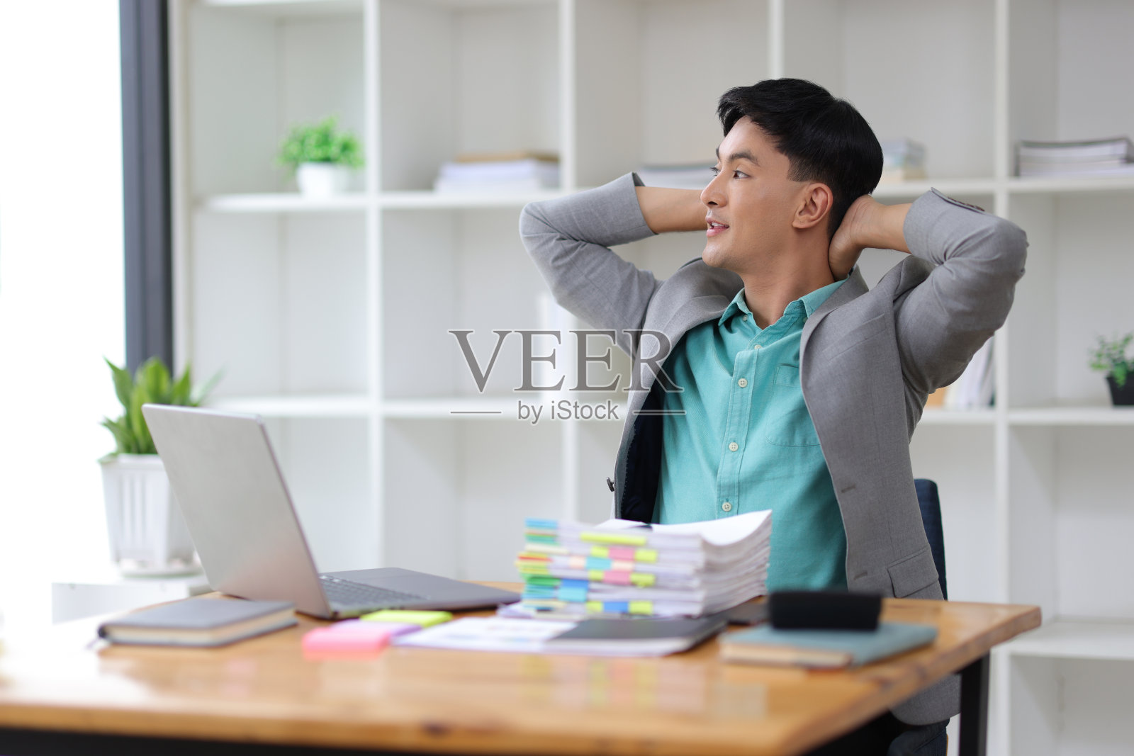 一个疼痛的商人在办公室工作后伸懒腰放松。照片摄影图片