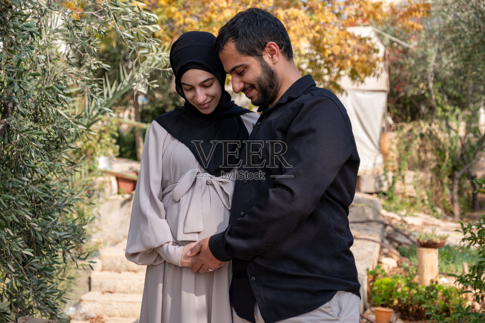 男人在花园里抚摸着妻子的肚子，为他的新宝宝感到兴奋照片摄影图片