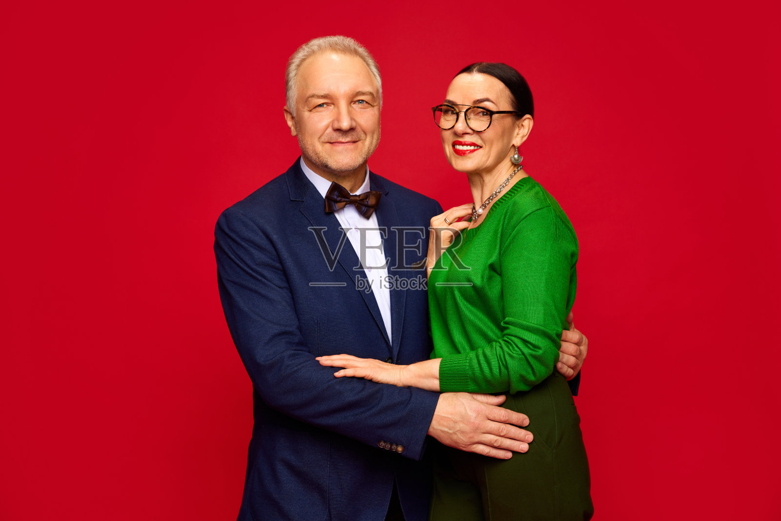 肖像优雅，美丽，时尚的高级夫妇，男人和女人庆祝周年纪念红色工作室背景。情人节照片摄影图片