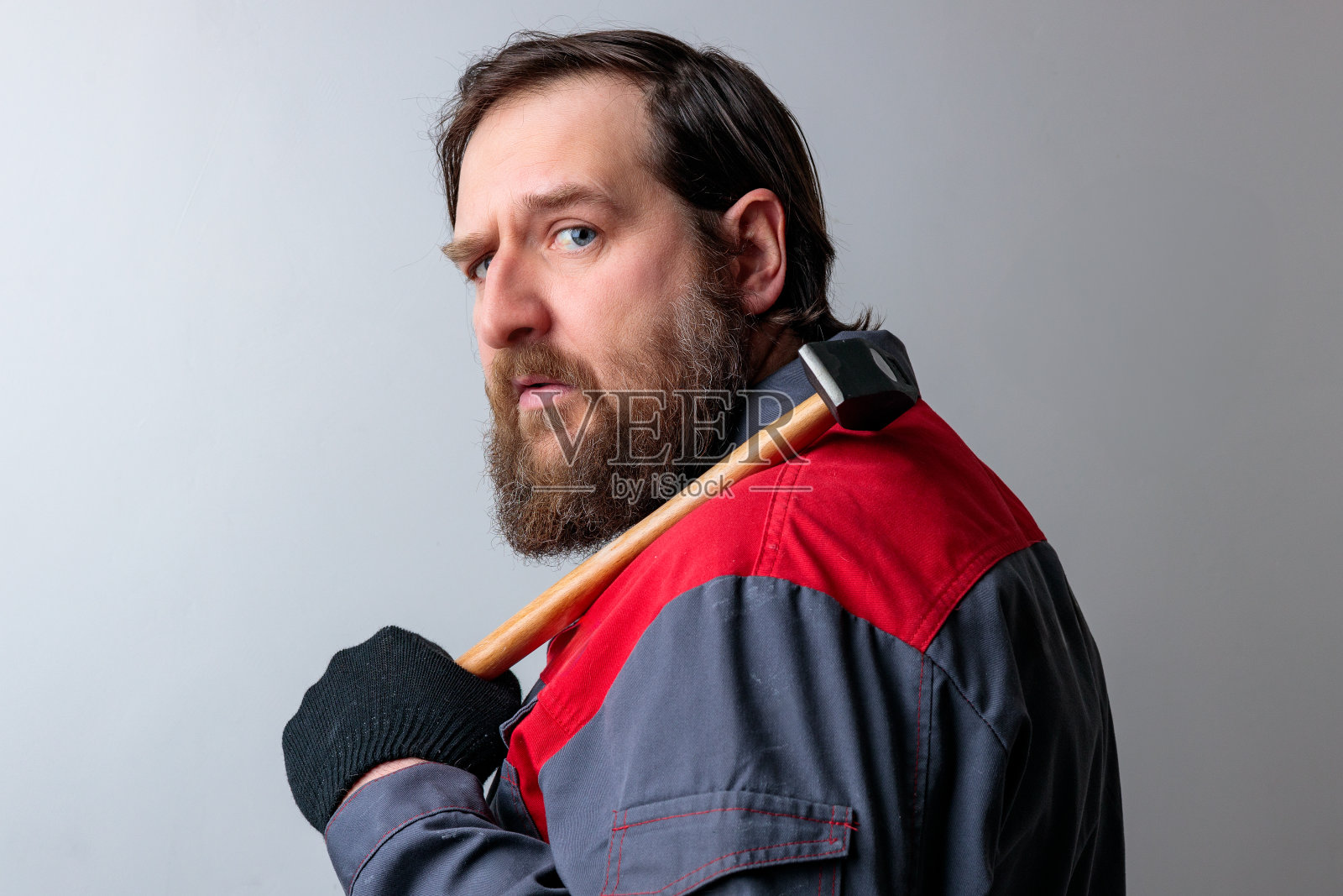 一个中年男子肩上扛着锤子转过身来，聚精会神地看着照片摄影图片