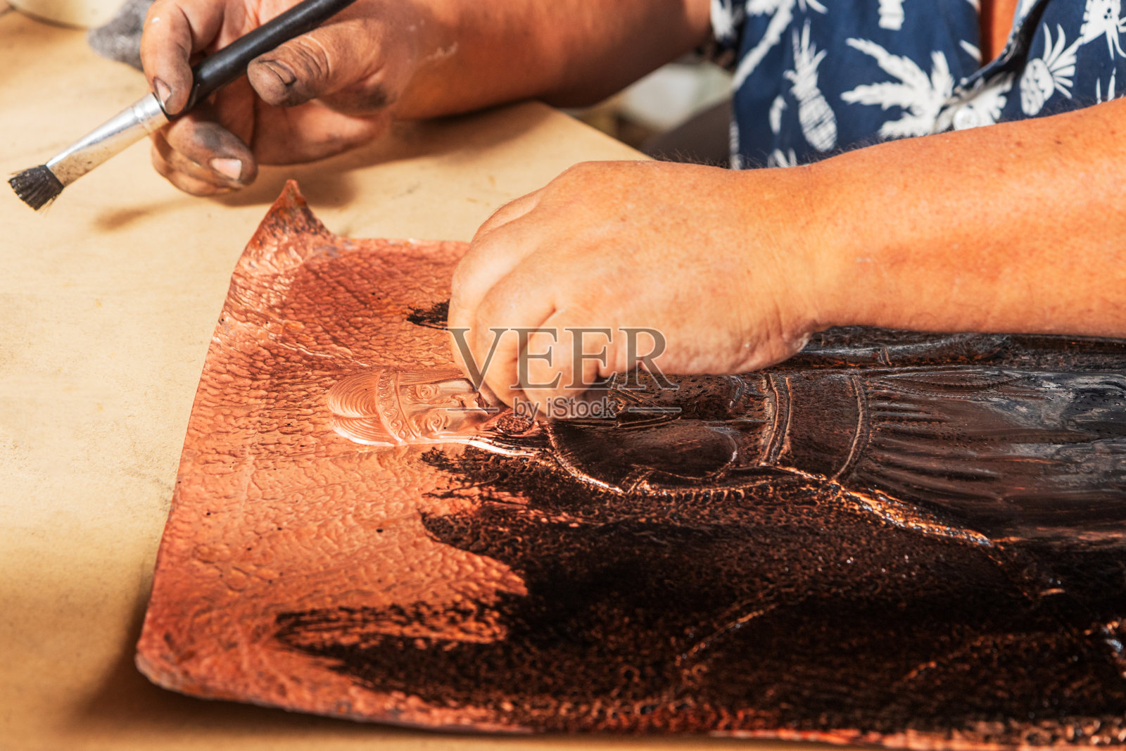 工匠正在给压花铜片上墨。照片摄影图片