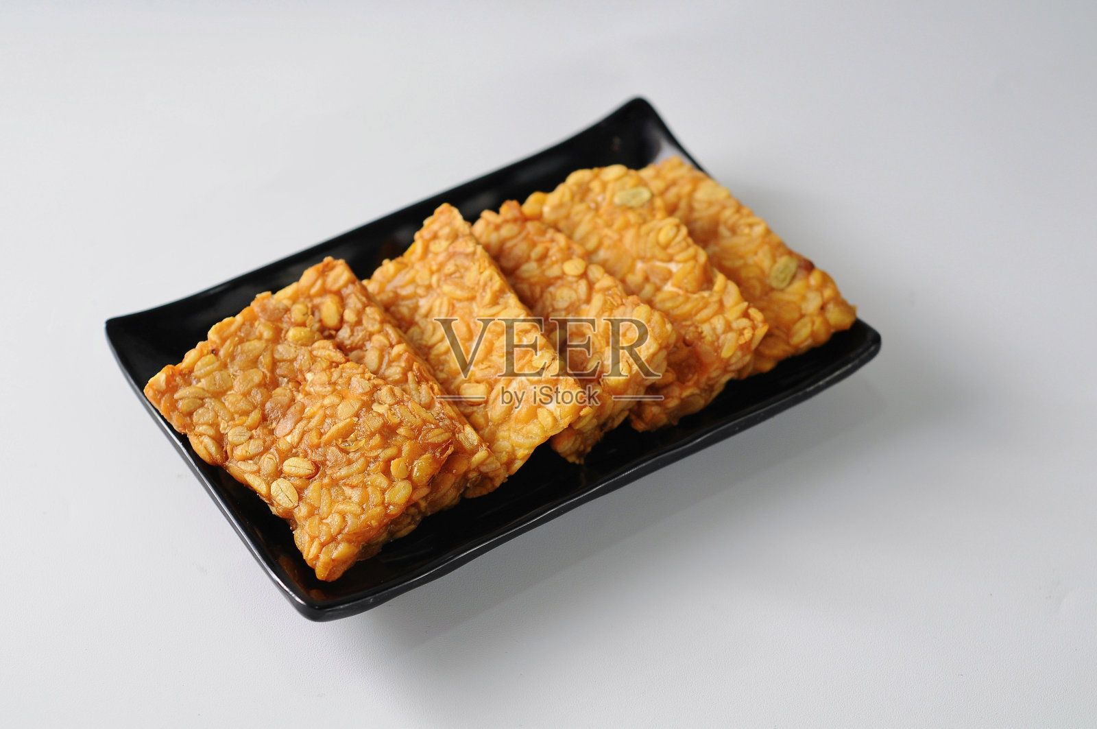 油炸豆豉装在黑色盘子里，照片摄影图片