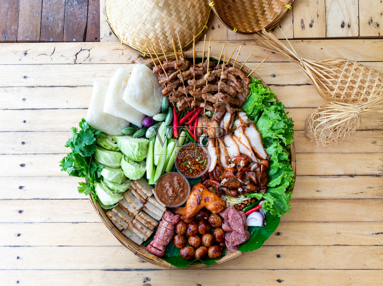 酸鱼酱和辣酱烤猪肉。新鲜蔬菜和辣椒在木盘里的香蕉叶上冲浪照片摄影图片