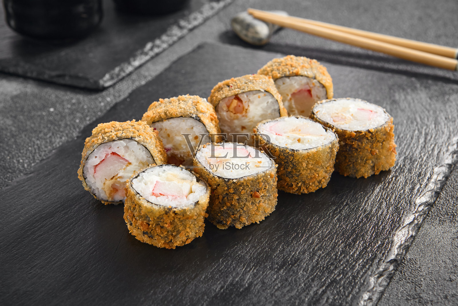 酥脆的天妇罗卷，里面有蟹和虾，完美的金棕色，放在极简主义的黑色石板上照片摄影图片