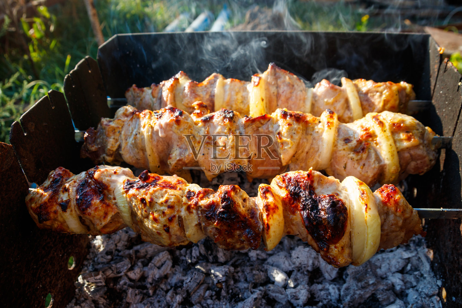 在金属串上烤烤肉串。烧烤时烤的肉。传统的东方菜，羊肉串。用木炭和火焰烧烤，野餐，街头小吃照片摄影图片