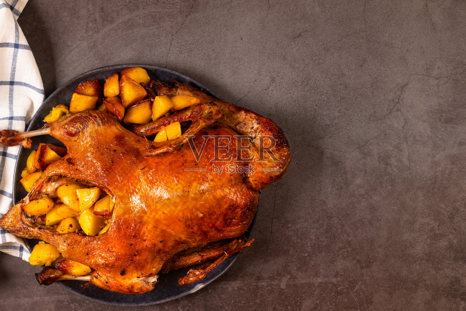 脆脆的整只烤鸭配土豆和洋葱。感恩节或圣诞节晚餐。照片摄影图片
