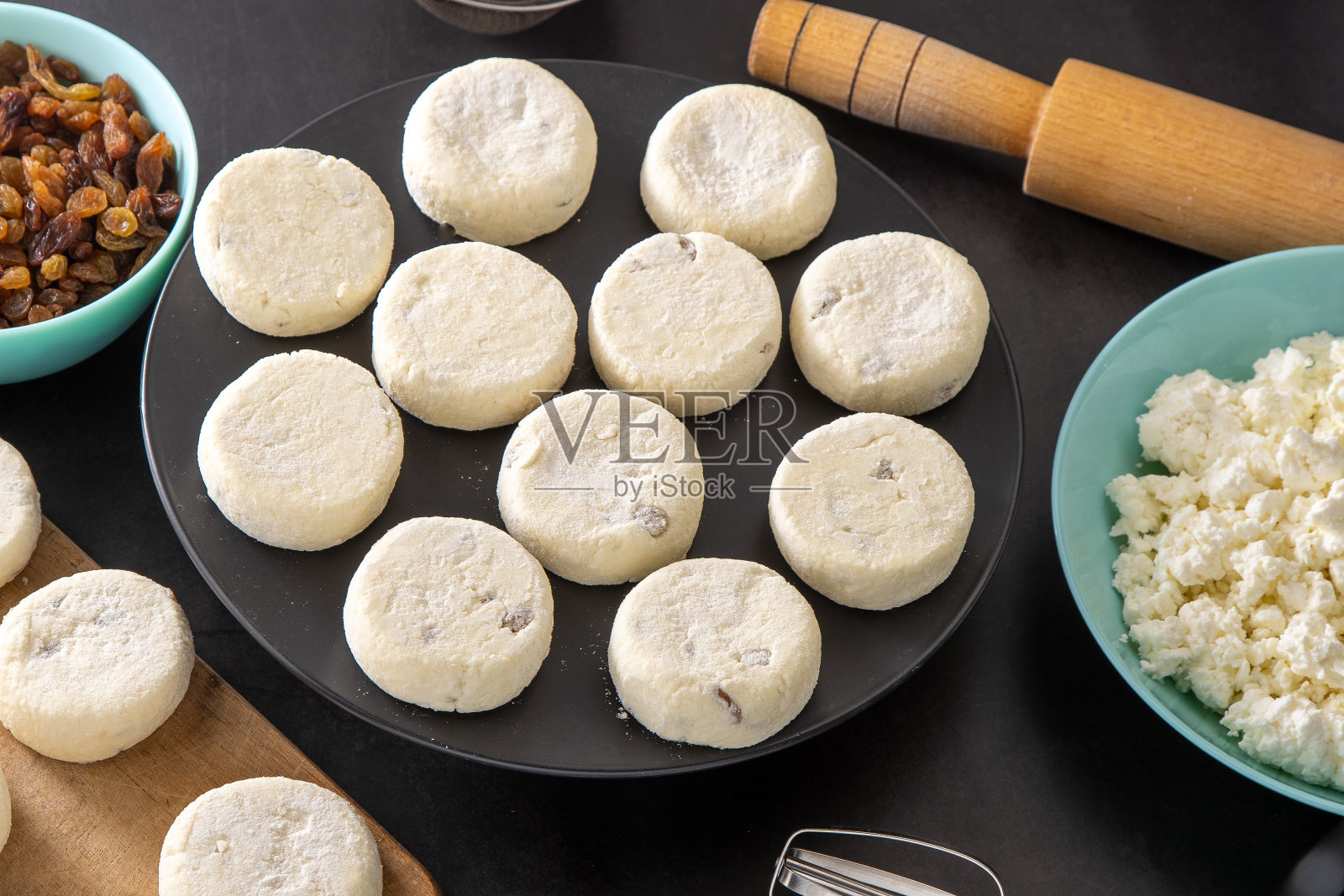 奶酪蛋糕由松软干酪和葡萄干制成。为早餐准备食物。Syrnik煎饼。黑色背景的圆形奶酪蛋糕。照片摄影图片