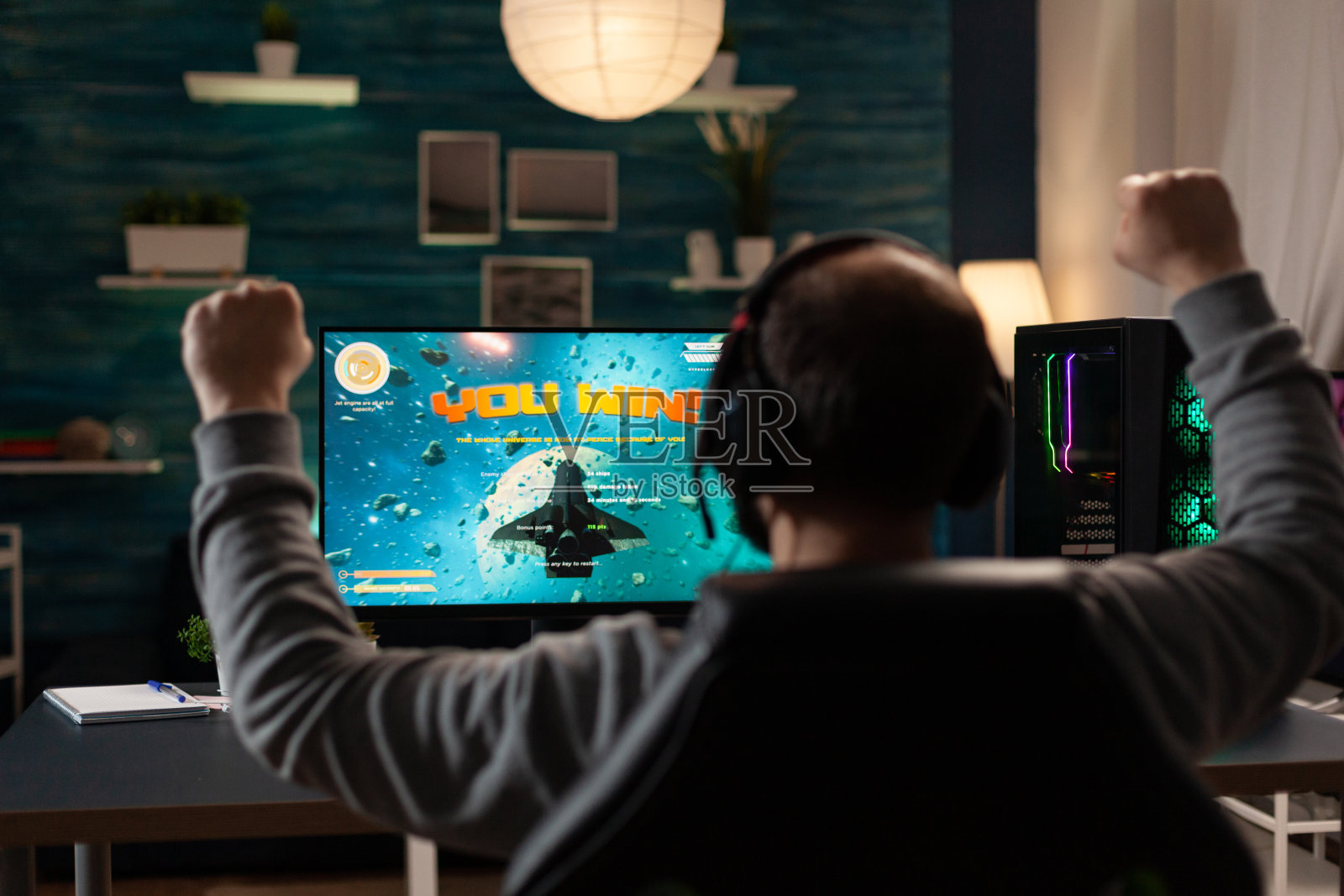 男子在电脑上赢得电子游戏后举手照片摄影图片