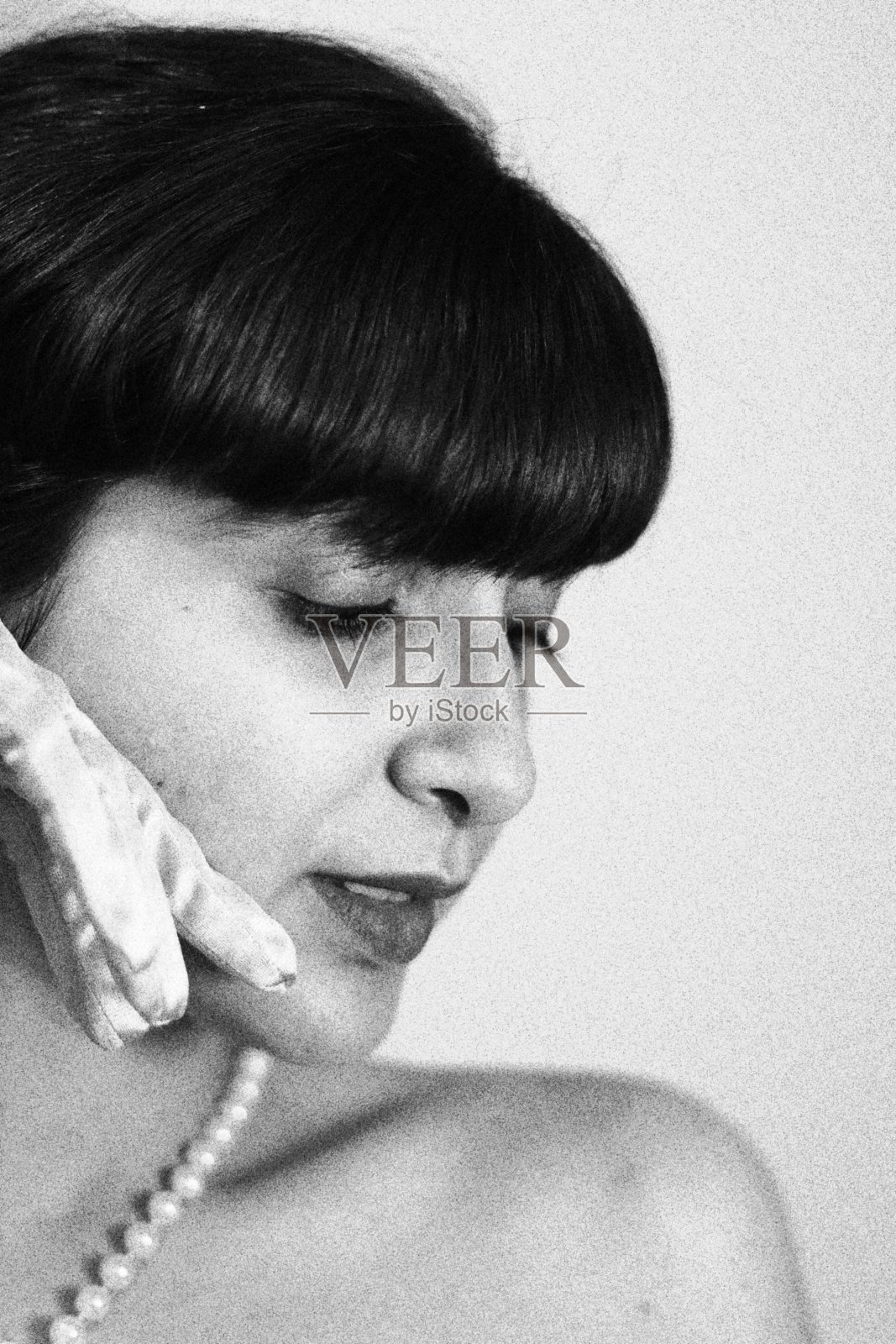 戴着珍珠和手套的年轻女子肖像。单色黑白调照片摄影图片