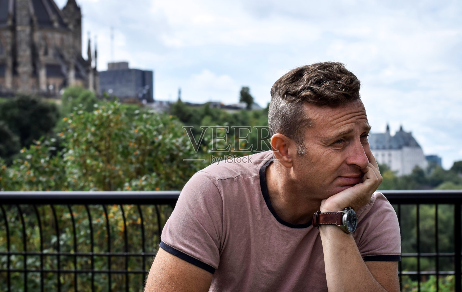 一个中年男子坐在外面的公园里沉思照片摄影图片