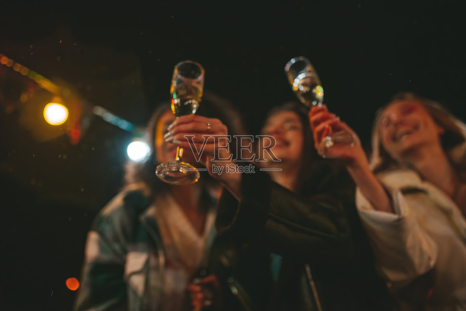 快乐微笑的女孩们在户外的圣诞露营车附近喝着起泡酒玩得很开心照片摄影图片