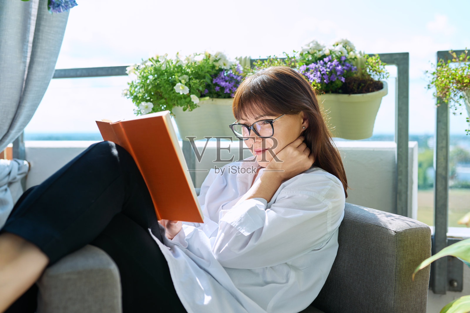 中年轻松快乐的女人读书，坐在家里照片摄影图片