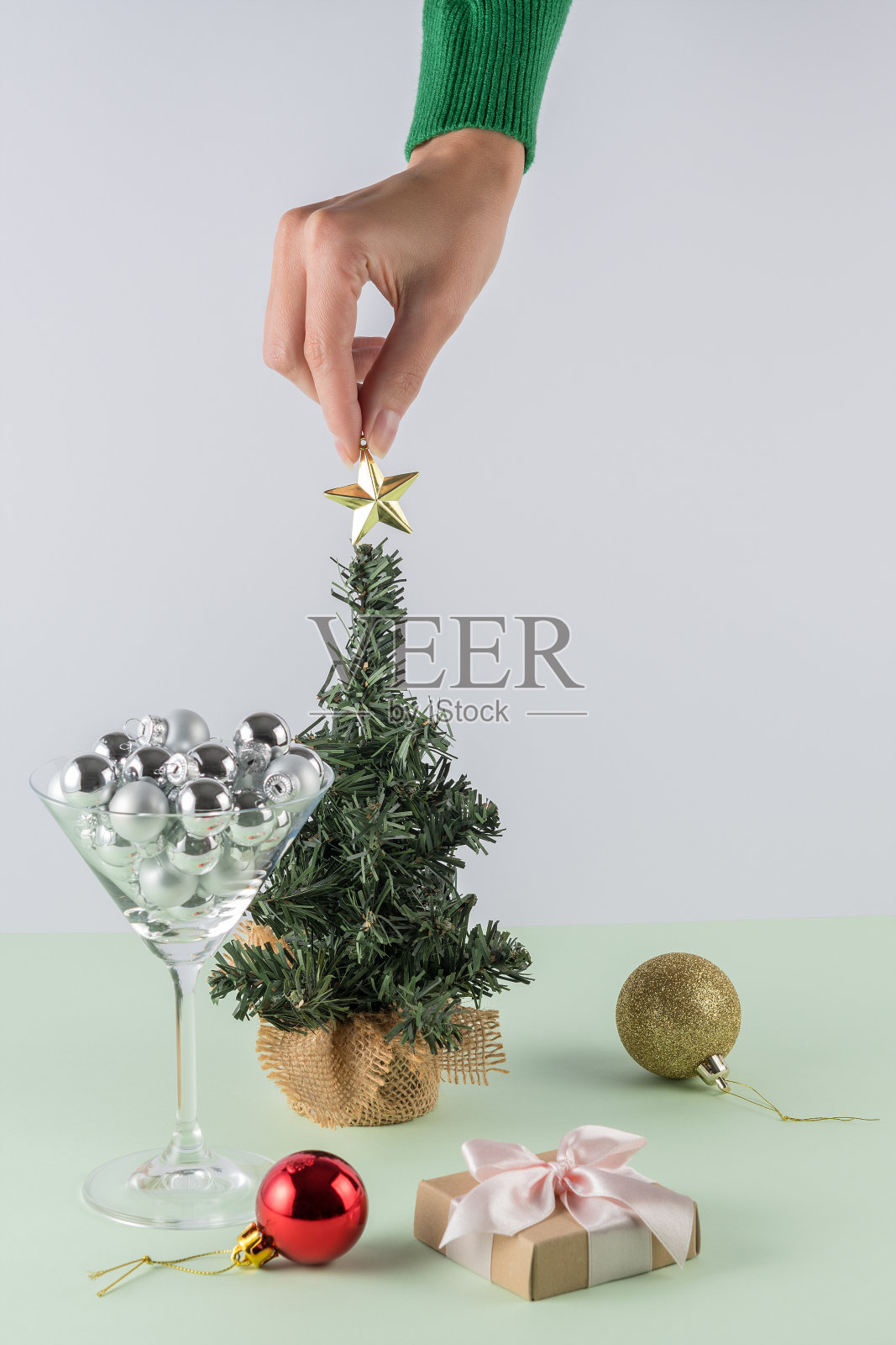 创意布局在柔和的薄荷绿色背景。妇女的手放置圣诞星星装饰。复古新年派对背景。照片摄影图片