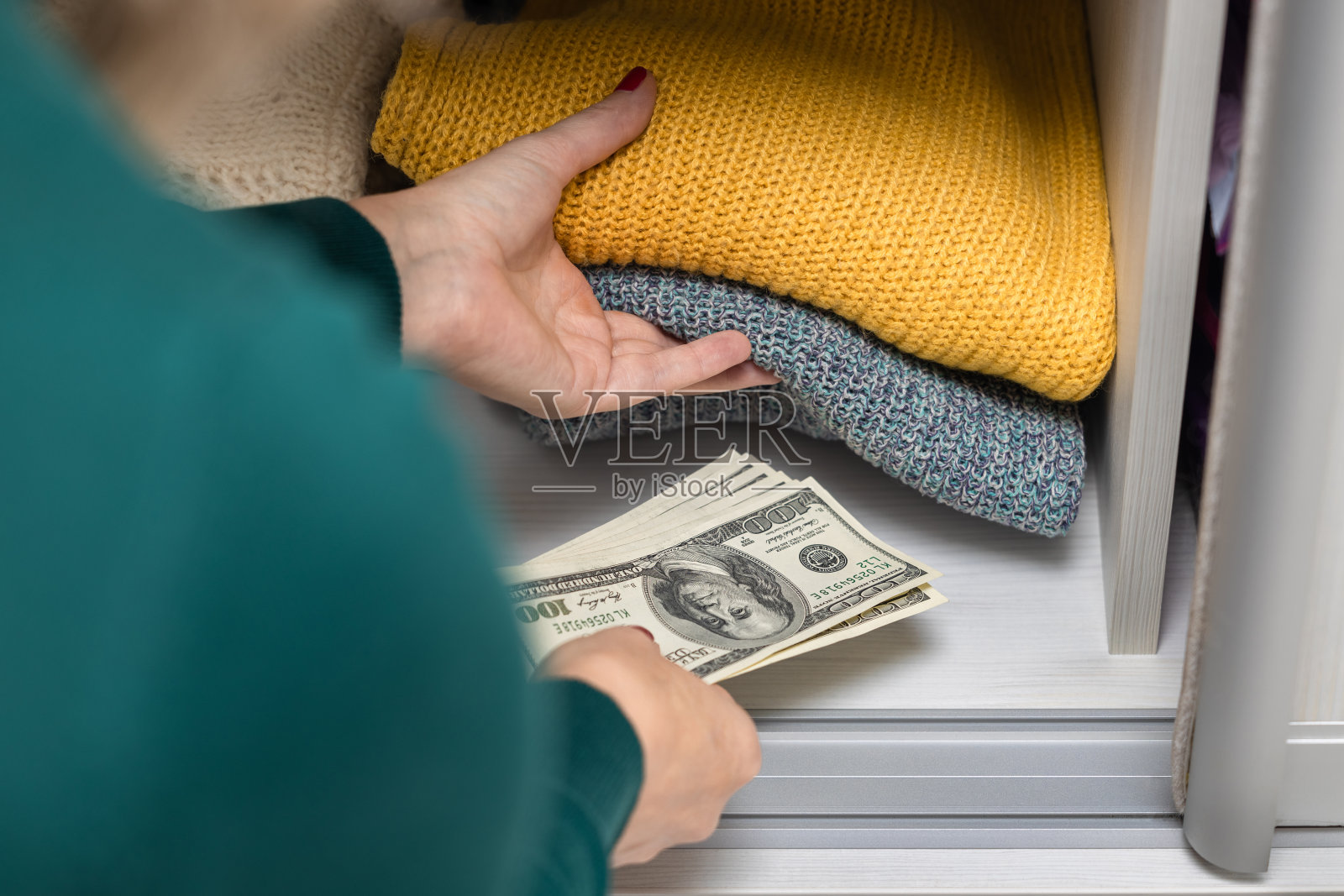 一个女人把美元和衣服一起藏在壁橱里照片摄影图片