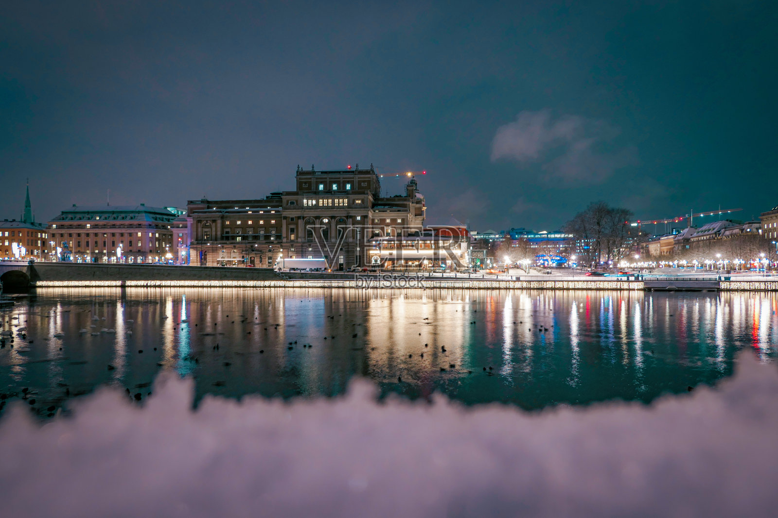 夜晚，河边灯火通明的建筑物映衬着天空照片摄影图片