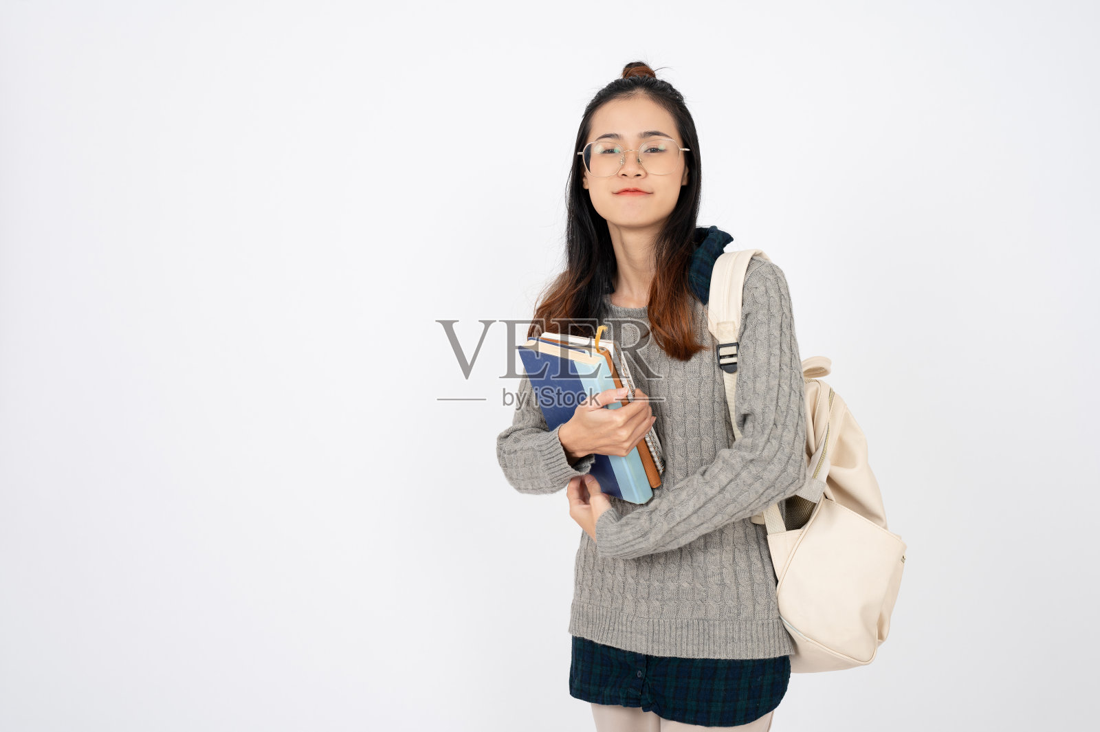 快乐可爱的亚洲大学生与书和背包在白色孤立的背景。照片摄影图片