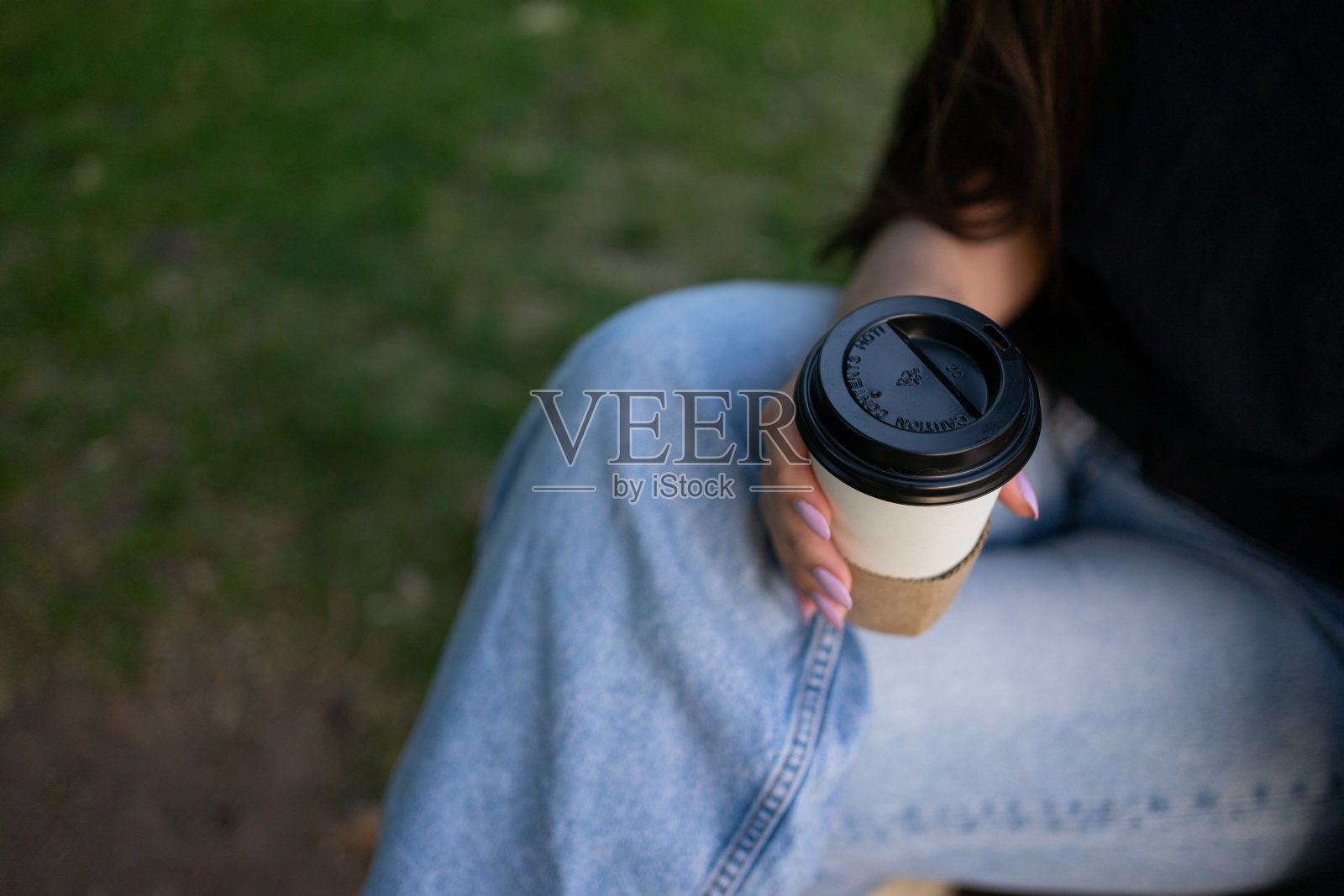 一个女孩坐在户外公园享受一杯咖啡。有空间用于复制。照片摄影图片