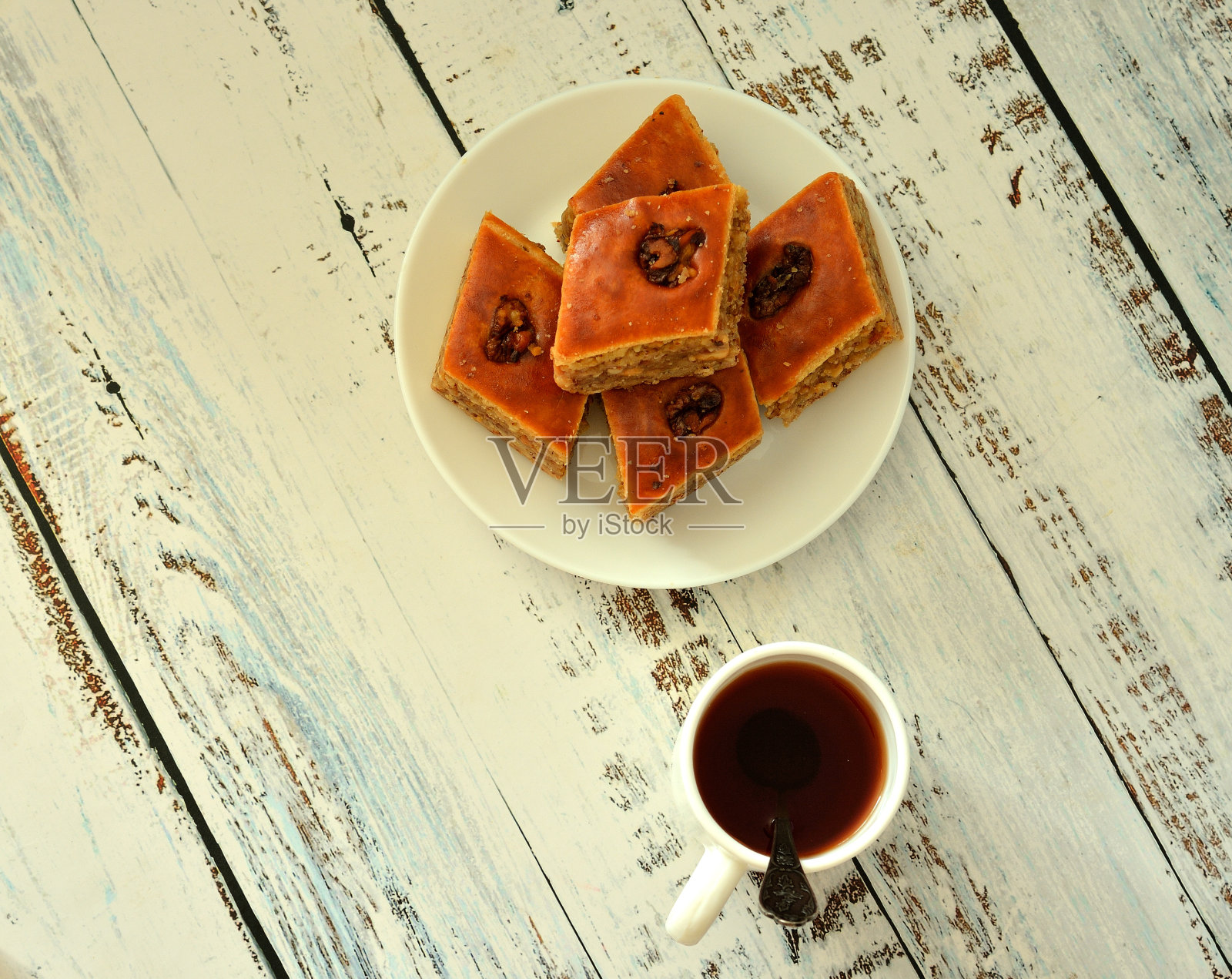 一杯热红茶和一个盘子里的新鲜蜂蜜果仁蜜饼在一个轻木桌。照片摄影图片