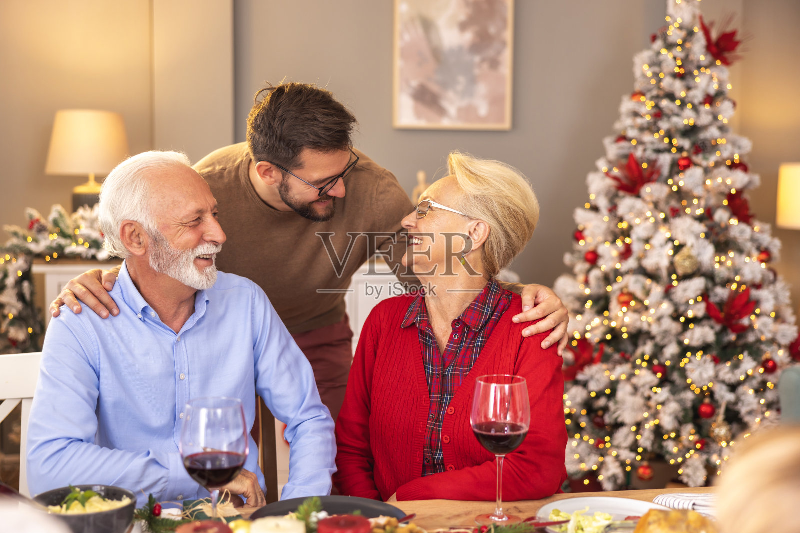 儿子在家里吃圣诞晚餐时拥抱父母照片摄影图片