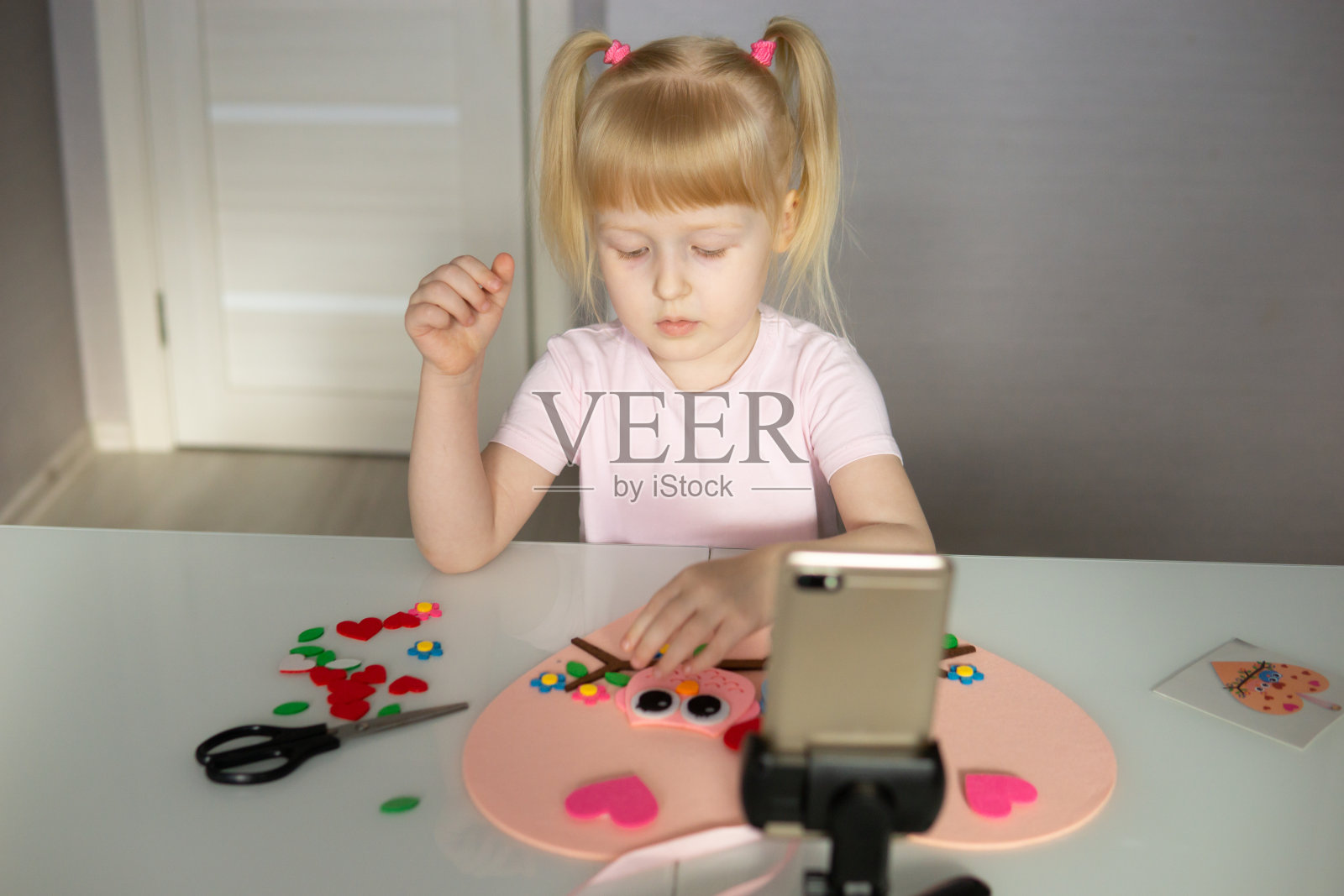 一个博主女孩为情人节做了一个心形的毛毡工艺品。儿童创意与手工的概念。照片摄影图片