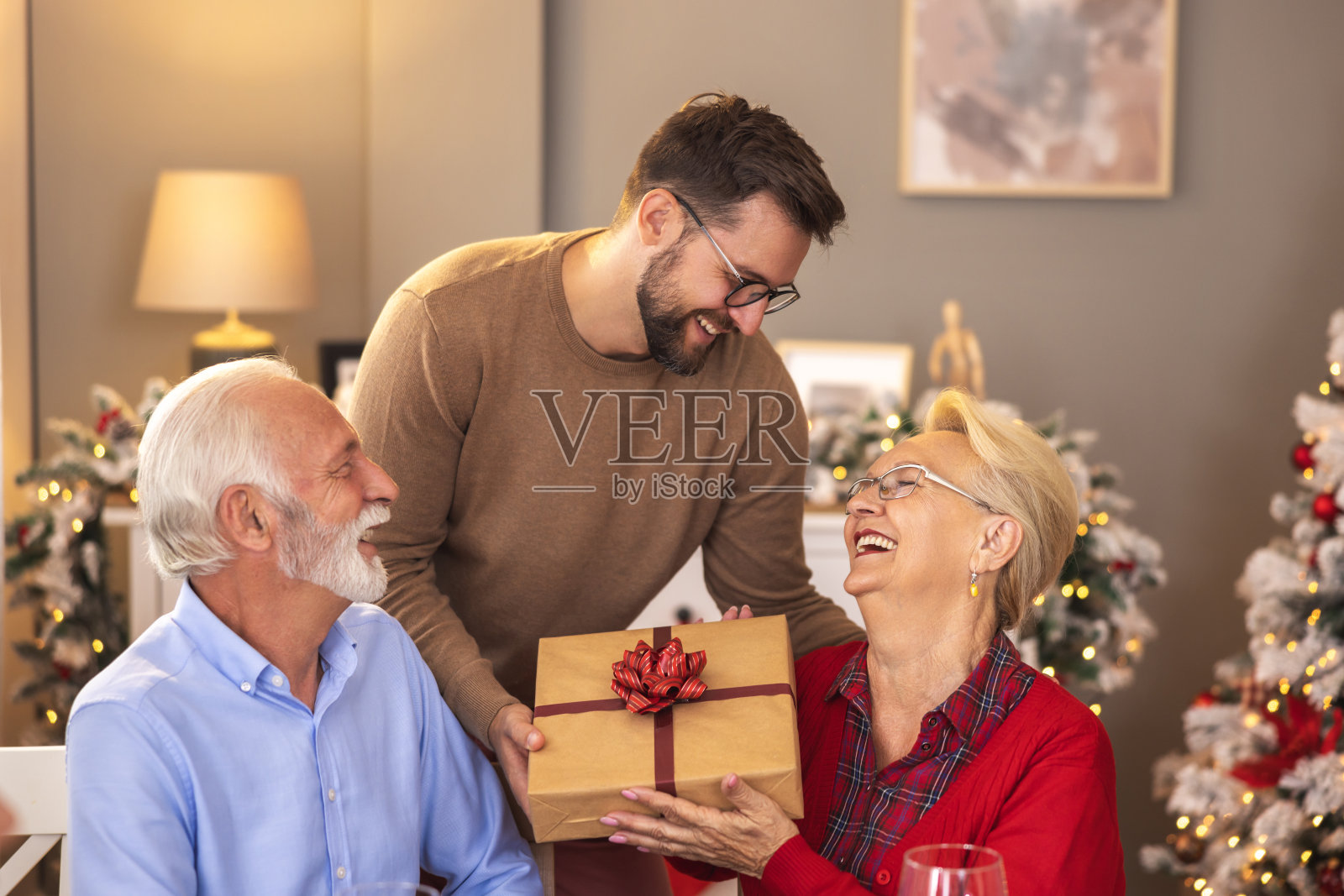 儿子和父母一起过圣诞节，给母亲送礼物照片摄影图片