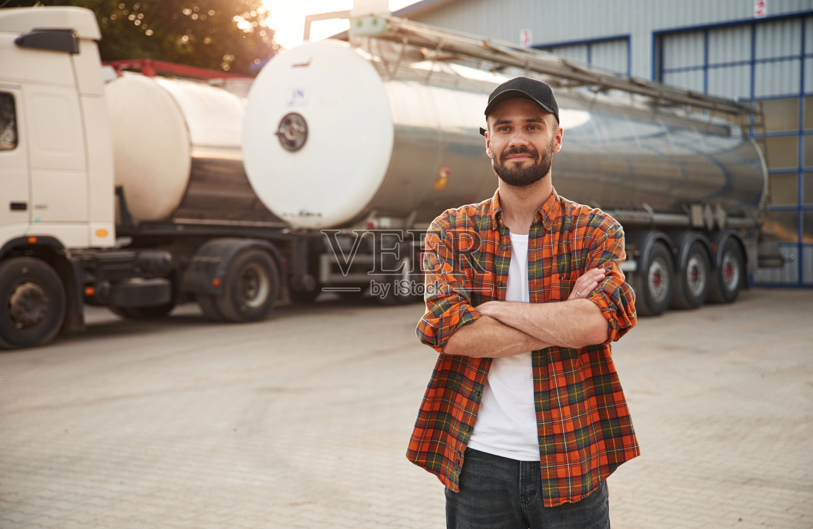 双臂交叉站立。穿着便服的年轻卡车司机照片摄影图片
